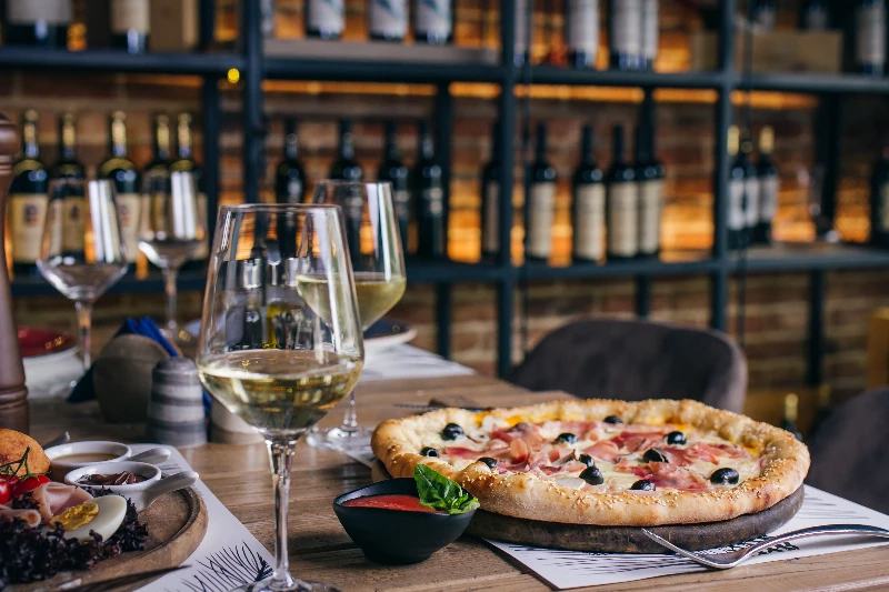 Blog 12 Pizza with prosciutto and olives with wine in restaurant
