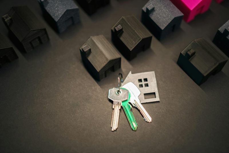 Miniature house models arranged with shiny keys, representing real estate investment and home ownership.