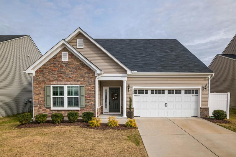 A modern suburban family house with a welcoming facade, featuring a lush front yard and driveway.