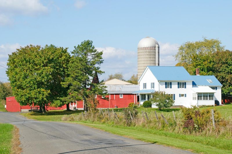 Rural farmhouse with barns and a silo surrounded by green fields in Hannacroix, New York.