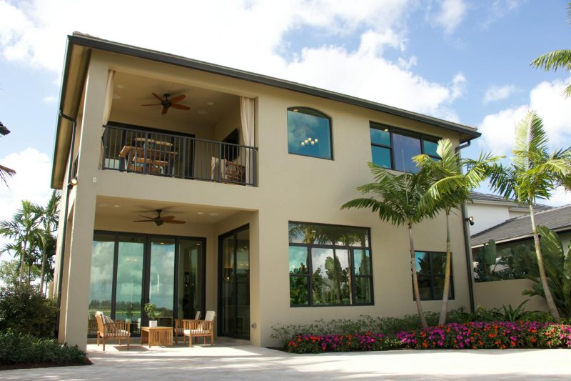Modern two-story home in Florida featuring a balcony, patio, and vibrant garden.