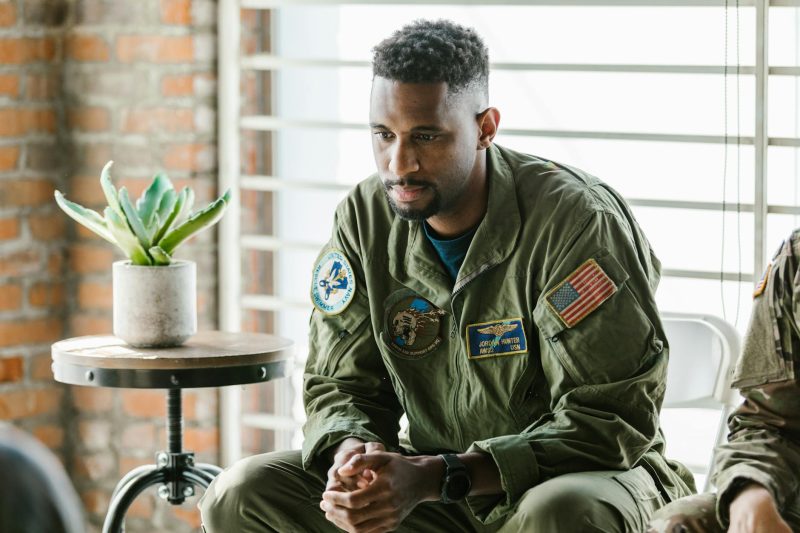 Thoughtful military veteran in uniform, listening attentively in a cozy indoor setting.