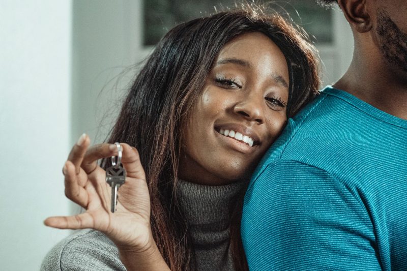 Blog 12 Joyful couple holding house keys, celebrating their new home purchase in a bright, welcoming setting.