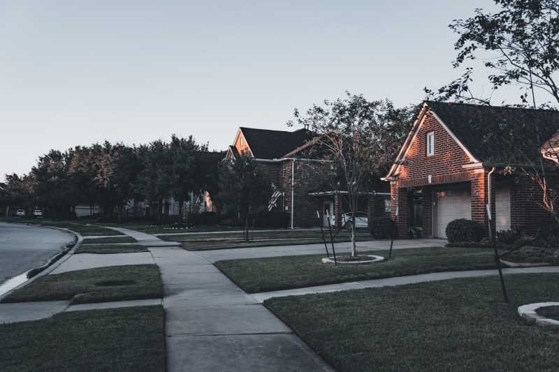 Serene suburban scene with brick houses and well-maintained lawns at dusk.